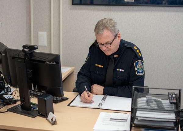 SMS employee sitting at a desk writing in a notebook