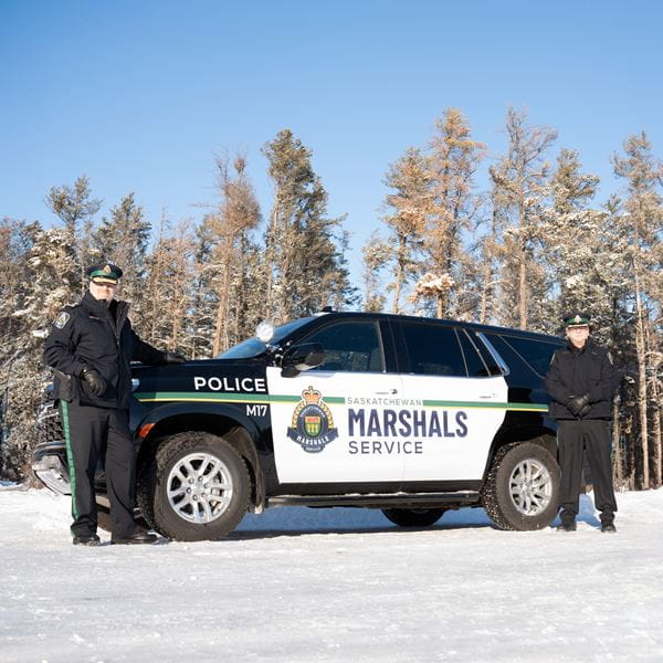 Two marshals standing outside a cruiser