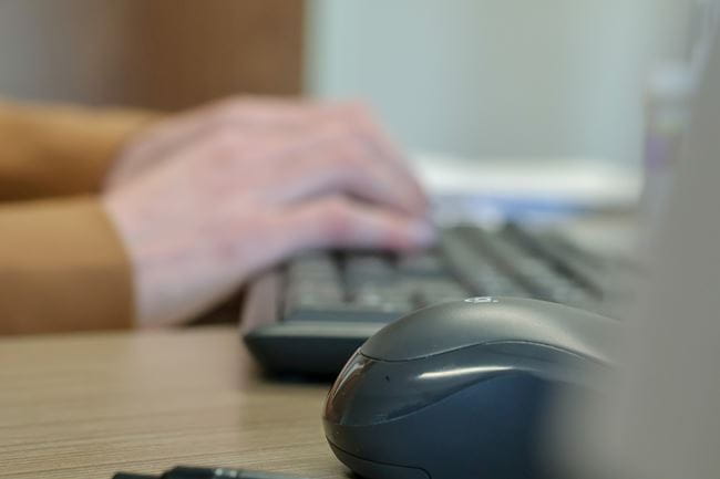 A civilian at the Saskatchewan Marshals Service types on a keyboard